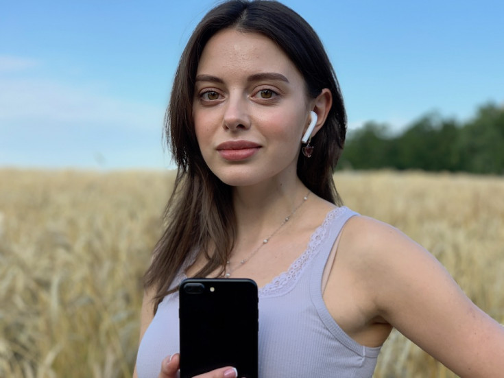 Девушка держит iPhone и слушает музыку через AirPods